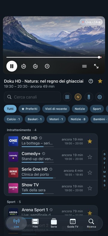 La schermata iniziale di Neverlag su iPhone: in alto il canale in onda con la barra del player e il tachimetro, poi la ricerca, filtri come Preferiti, Calcio e Notizie e l’elenco canali per gruppi con il tempo rimanente